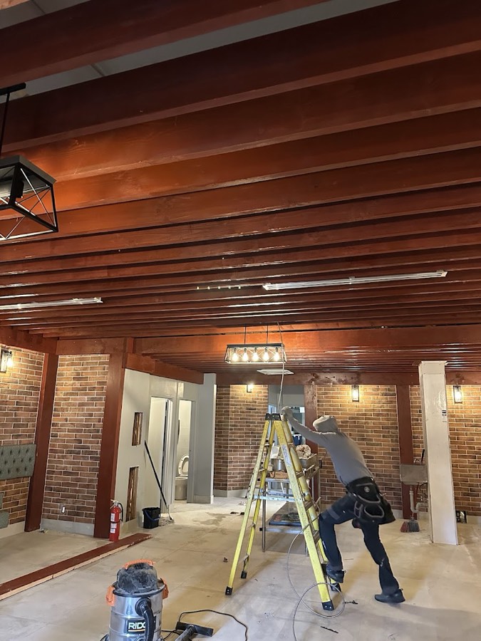 Electrician on a ladder working on ceiling wiring during a fit-out